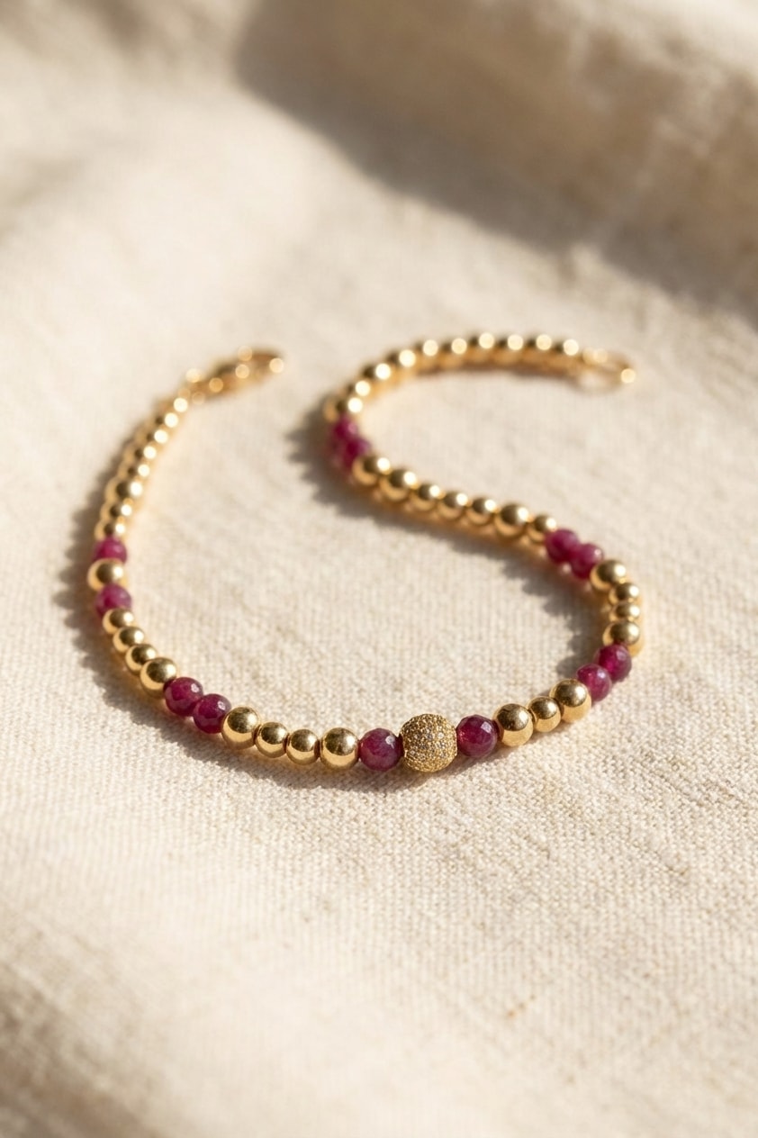 Pulsera Bola de Fuego con Rubí sobre lino cremoso, flat lay editorial en oro laminado 18k NJL Jewelry