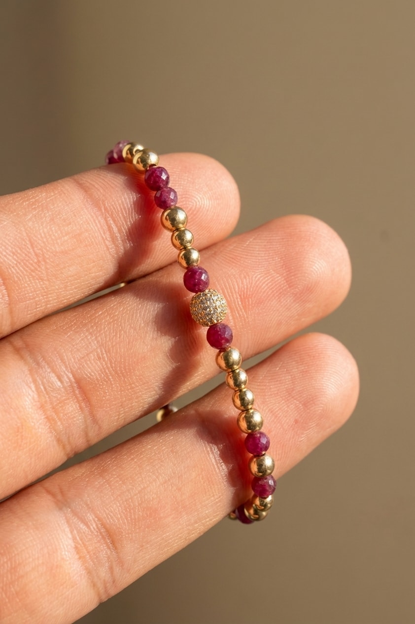 Pulsera Bola de Fuego con Rubí detalle macro sostenida entre dedos en oro laminado 18k NJL Jewelry