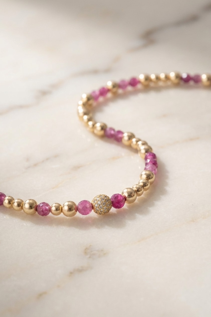 Pulsera Bola de Fuego con Rubí flat lay sobre mármol cremoso, composición elegante en oro laminado 18k NJL Jewelry