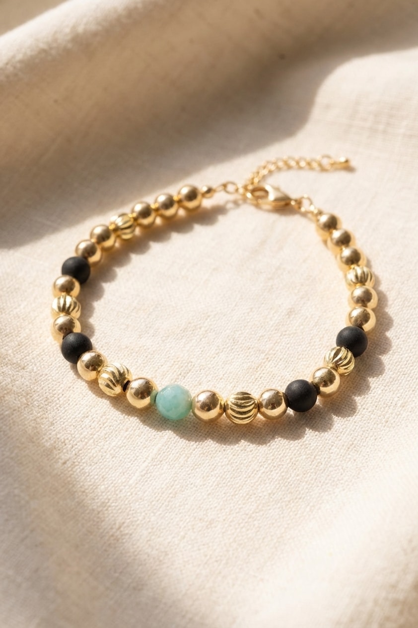 Pulsera Esmeralda Central Media sobre lino cremoso, flat lay editorial en oro laminado 18k NJL Jewelry