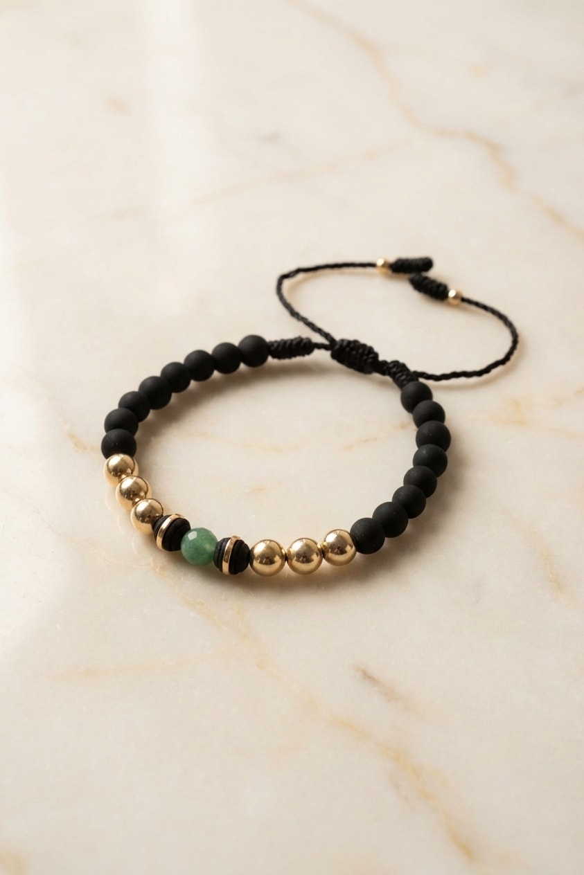 Pulsera Neopreno Esmeralda flat lay sobre mármol cremoso, composición elegante en oro laminado 18k NJL Jewelry