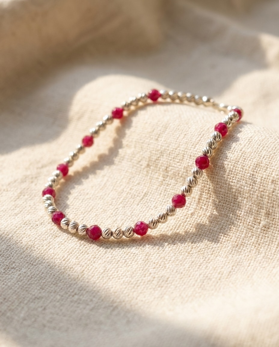 Pulsera Plata 925 con Rubí 3mm sobre lino cremoso, flat lay editorial en oro laminado 18k NJL Jewelry