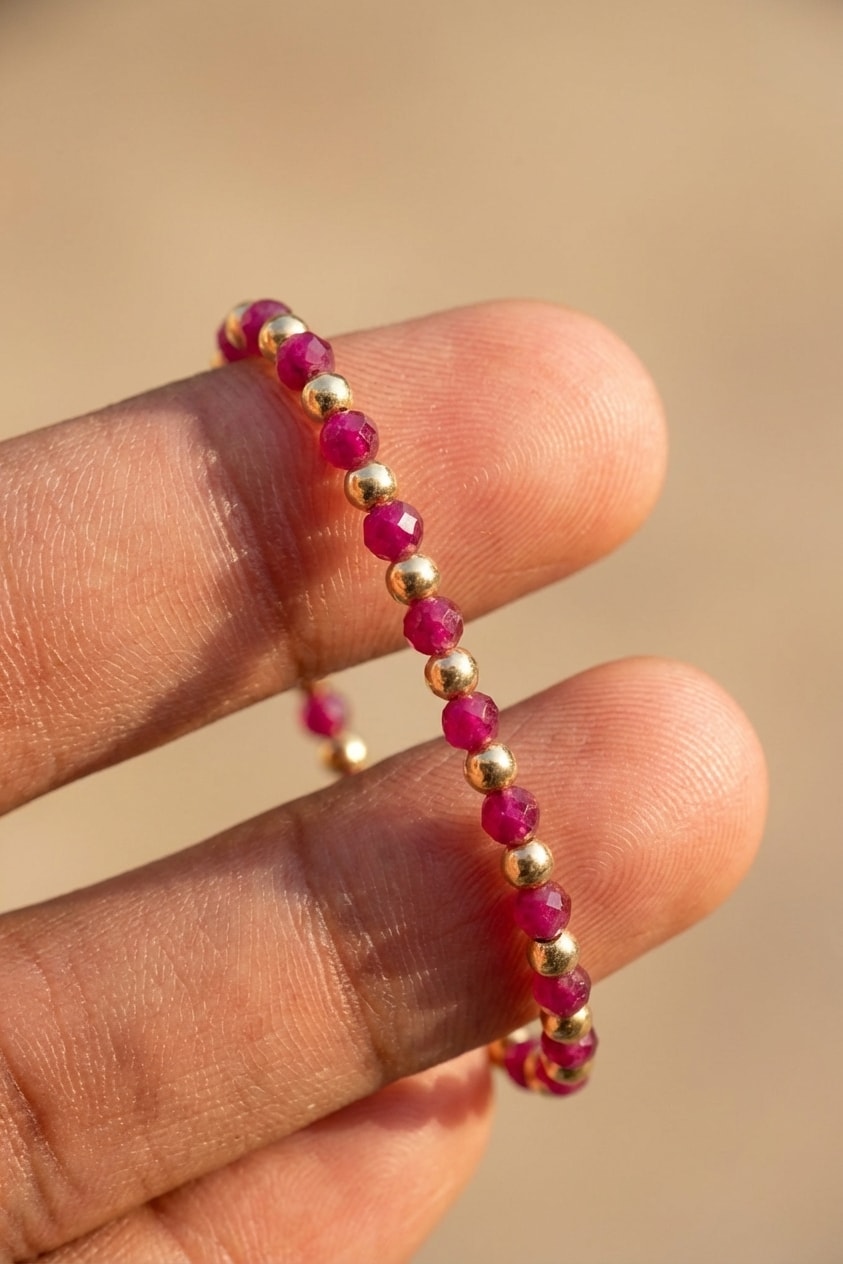 Pulsera Rubí Intercalado Balín 4mm detalle macro sostenida entre dedos en oro laminado 18k NJL Jewelry