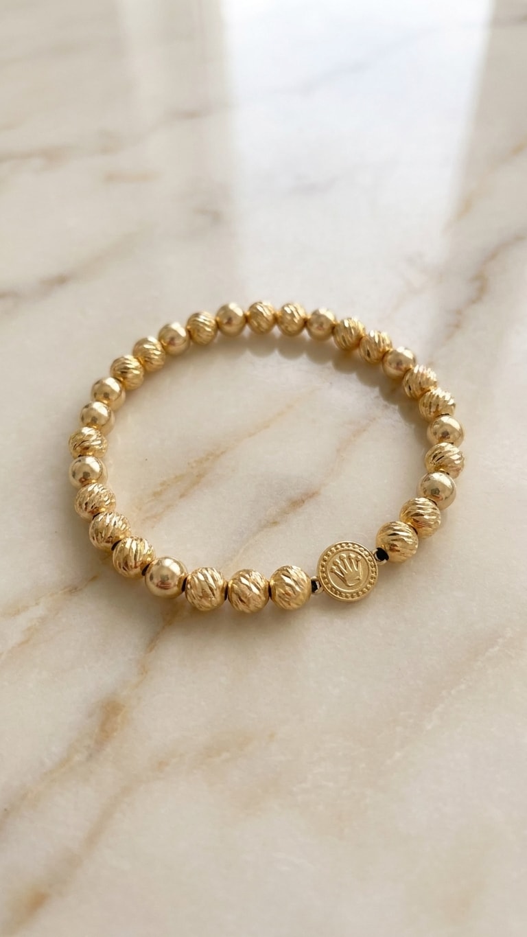 Pulsera balines diamantados gruesos con medalla sello premium oro laminado 18k flat lay sobre mármol cremoso, composición elegante NJL Jewelry